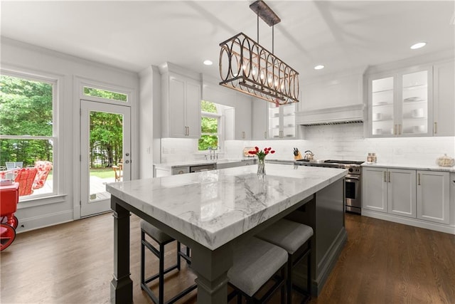kitchen featuring a kitchen breakfast bar, high end stove, white cabinets, decorative backsplash, and light stone counters