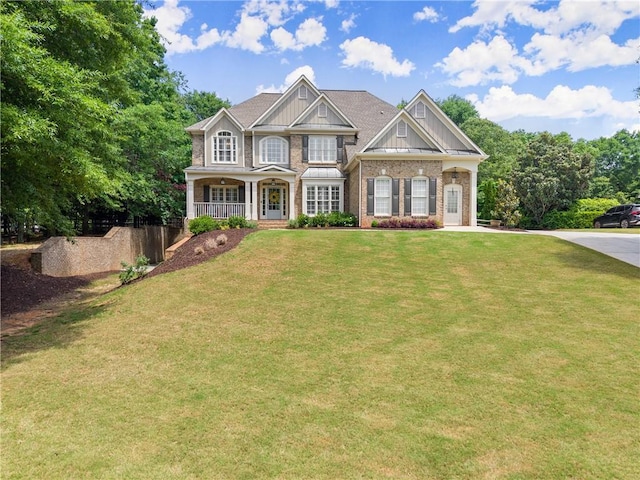 craftsman house with a porch, a front yard, and brick siding