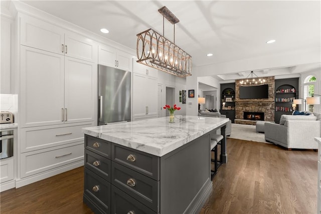 kitchen with stainless steel refrigerator, a chandelier, white cabinets, dark wood finished floors, and a kitchen island