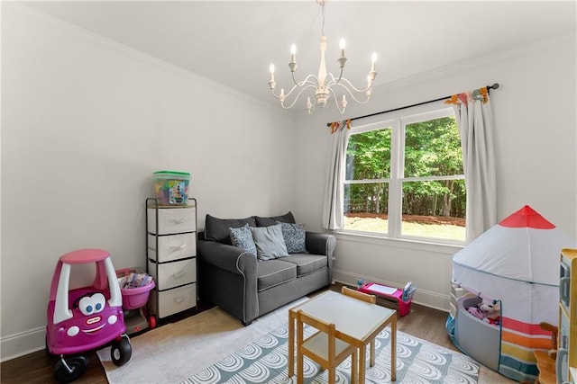 recreation room with a chandelier, ornamental molding, baseboards, and wood finished floors