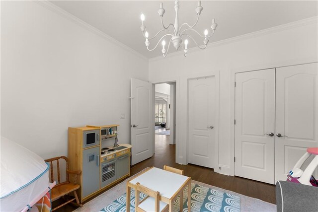 rec room with crown molding, wood finished floors, and a chandelier