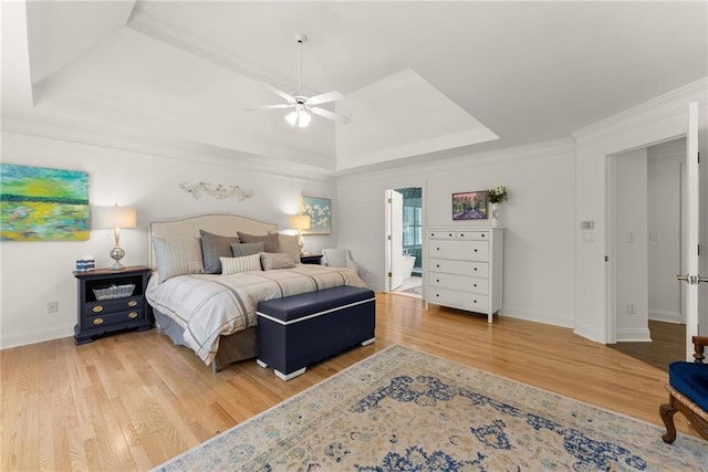 bedroom featuring a tray ceiling, wood finished floors, baseboards, ceiling fan, and crown molding