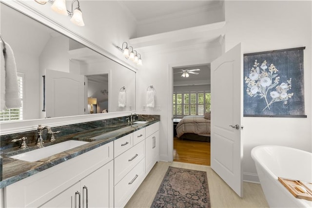 bathroom with ceiling fan, wood finished floors, a freestanding tub, double vanity, and crown molding