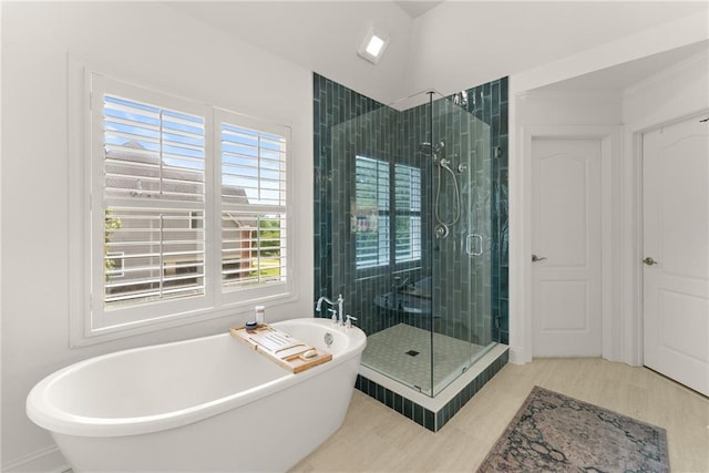 bathroom featuring a shower stall, a freestanding bath, and wood finished floors