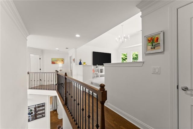 hall with an upstairs landing, wood finished floors, a chandelier, crown molding, and recessed lighting