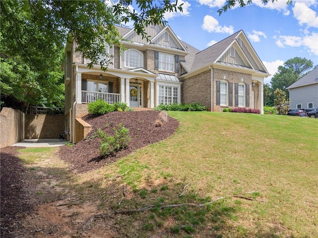 craftsman house with board and batten siding, brick siding, a front yard, and a porch
