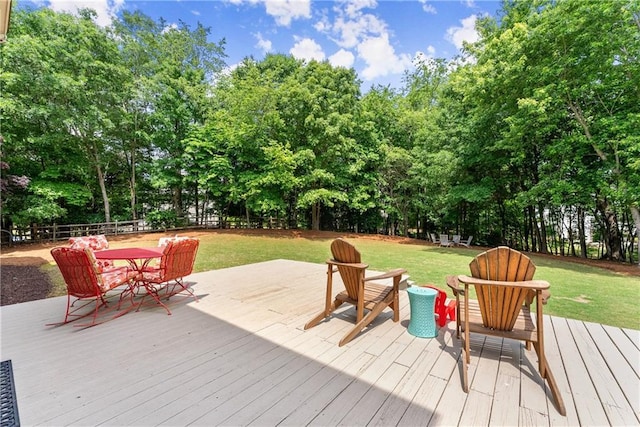 wooden terrace with outdoor dining space and view of wooded area