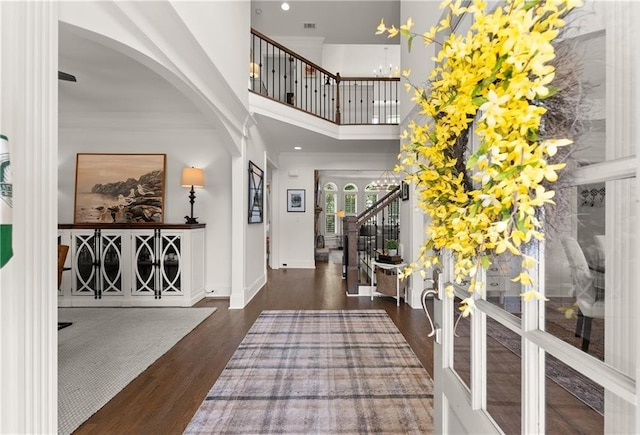 foyer entrance with a high ceiling, arched walkways, wood finished floors, baseboards, and stairway
