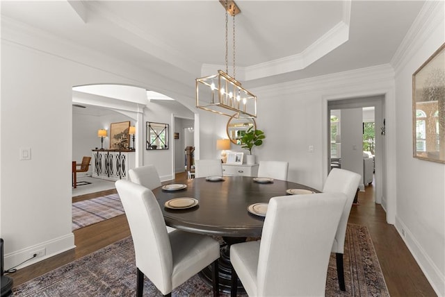 dining room featuring arched walkways, wood finished floors, crown molding, baseboards, and a chandelier