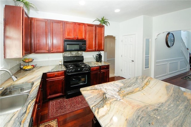 kitchen with dark hardwood / wood-style flooring, sink, light stone counters, and black appliances