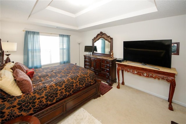 carpeted bedroom with a raised ceiling