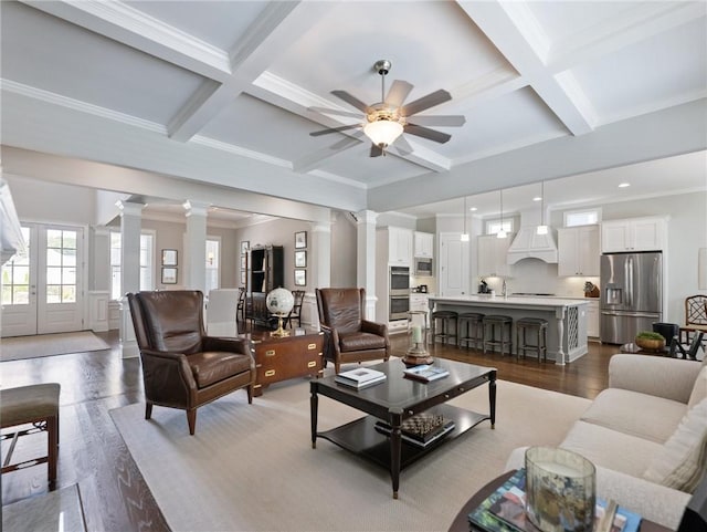 living room featuring coffered ceiling, hardwood / wood-style floors, beam ceiling, and ornate columns