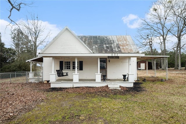 view of front of house with a porch, a front yard, metal roof, fence, and an attached carport