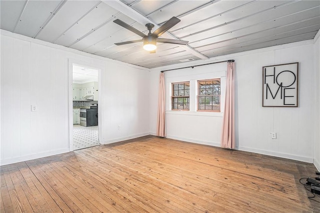 spare room with light wood finished floors, ceiling fan, and baseboards