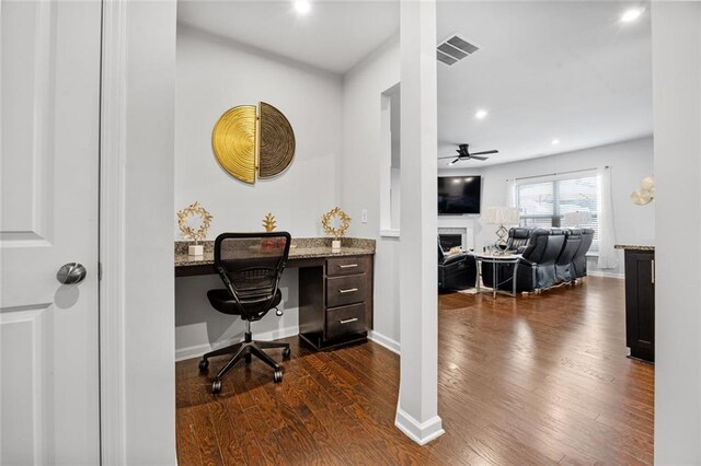 home office with ceiling fan, dark hardwood / wood-style floors, and built in desk