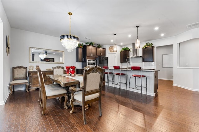 dining area with dark hardwood / wood-style flooring, sink, and an inviting chandelier