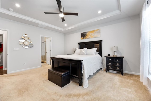 bedroom with light colored carpet, a raised ceiling, ceiling fan, and ensuite bathroom