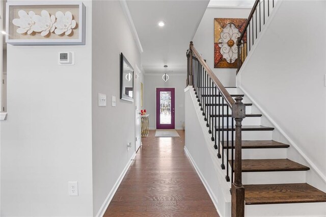 entryway with ornamental molding and dark hardwood / wood-style floors