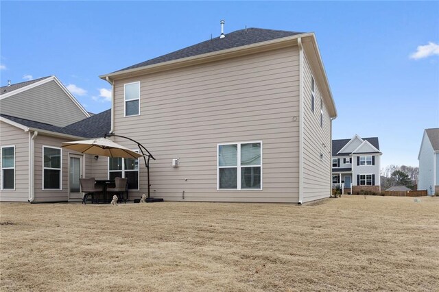 back of house featuring a lawn and a patio area