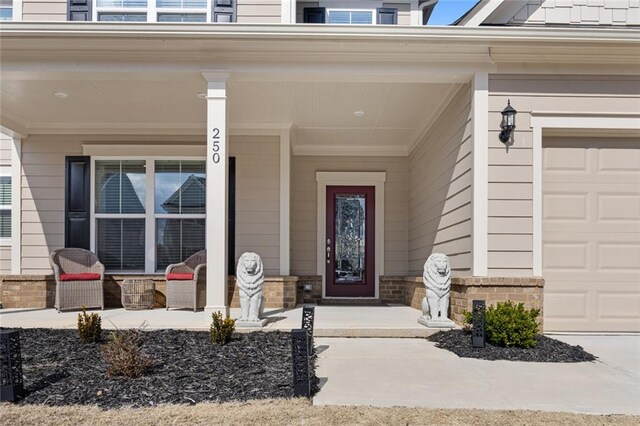 view of exterior entry featuring a porch and a garage