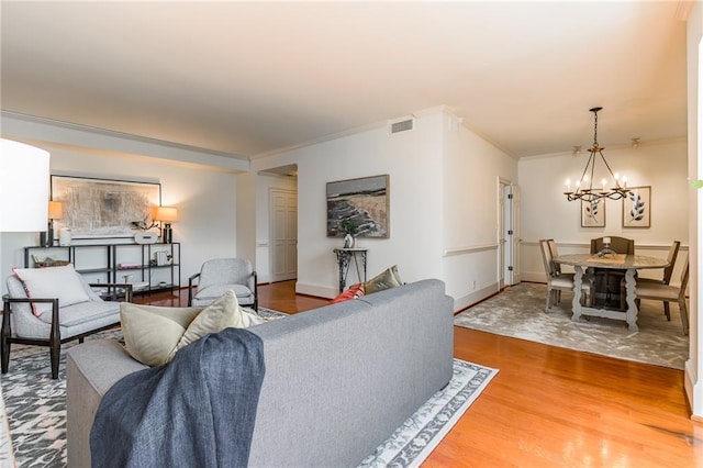 living room featuring hardwood / wood-style flooring, crown molding, and a notable chandelier