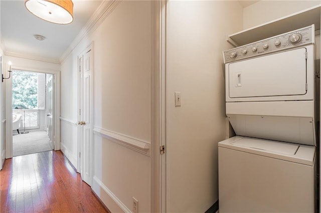 laundry area with hardwood / wood-style floors, crown molding, and stacked washer / dryer