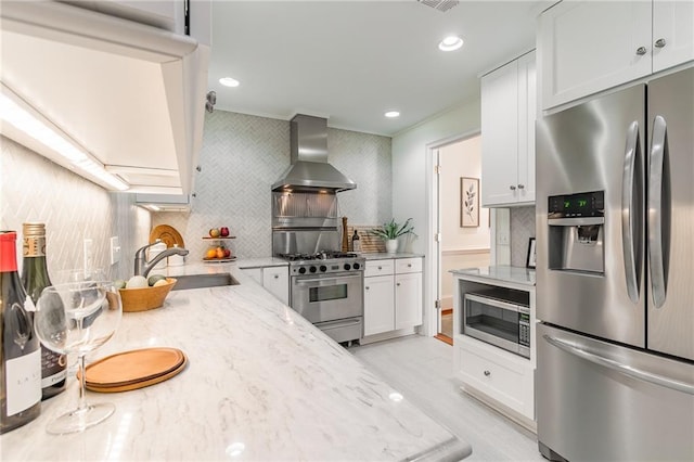 kitchen with sink, white cabinets, light stone counters, stainless steel appliances, and wall chimney exhaust hood