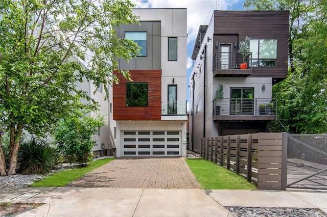 167 Sampson St NE, Atlanta, GA 30312 - contemporary home featuring decorative driveway, an attached garage, a balcony, stucco siding, and a gate
