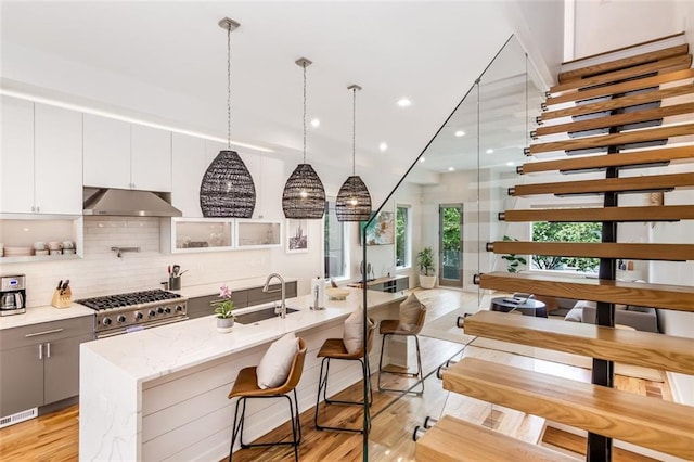 167 Sampson St NE, Atlanta, GA 30312 - kitchen with under cabinet range hood, tasteful backsplash, light wood-style flooring, a kitchen island with sink, and white cabinetry