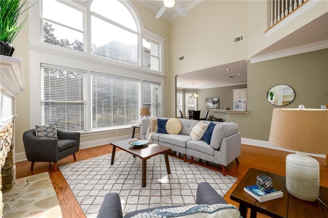 living room with light hardwood / wood-style flooring, ornamental molding, and a healthy amount of sunlight