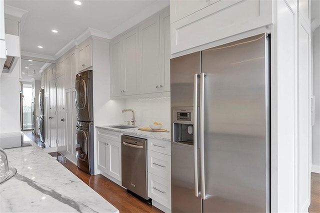 2575 Peachtree Rd NE Unit 11D, Atlanta, GA 30305 - kitchen with sink, appliances with stainless steel finishes, white cabinetry, stacked washer and clothes dryer, and light stone countertops