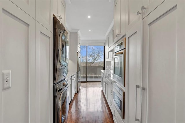 2575 Peachtree Rd NE Unit 11D, Atlanta, GA 30305 - kitchen with dark wood-type flooring, appliances with stainless steel finishes, white cabinets, and stacked washing maching and dryer