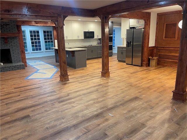 1321 Earle Ct SE, Conyers, GA 30013 - kitchen featuring appliances with stainless steel finishes, white cabinets, light wood finished floors, light countertops, and wooden walls