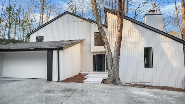 back of house featuring a chimney and an attached garage