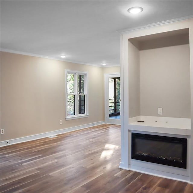 unfurnished living room featuring baseboards, a glass covered fireplace, wood finished floors, crown molding, and recessed lighting