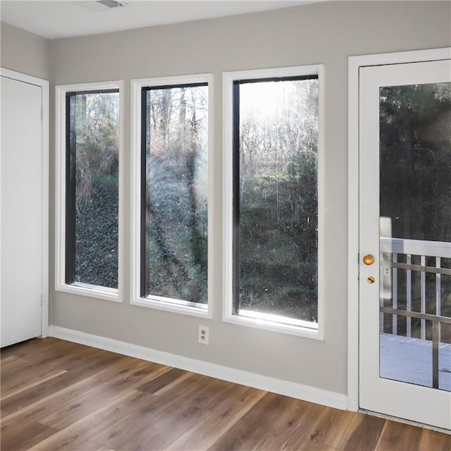 doorway featuring baseboards and wood finished floors