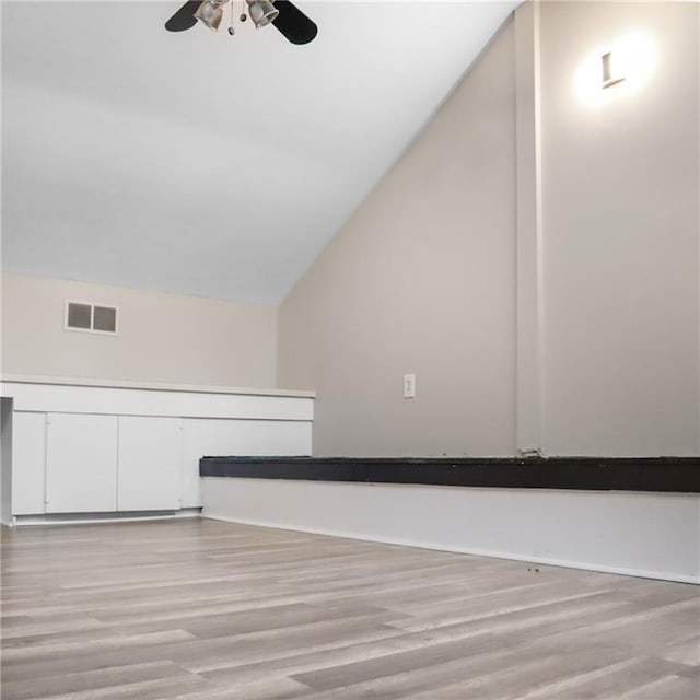 additional living space with light wood-style floors, visible vents, vaulted ceiling, and ceiling fan