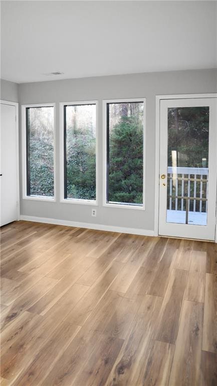 spare room with baseboards and wood finished floors