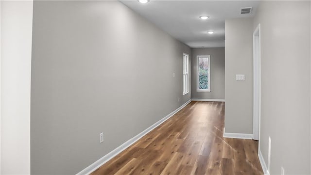 corridor featuring wood finished floors, visible vents, and baseboards