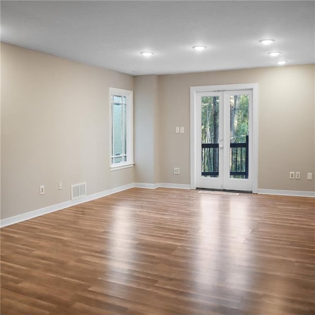 unfurnished room with french doors, wood finished floors, visible vents, and baseboards