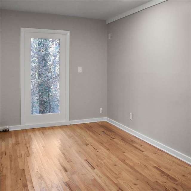 spare room featuring plenty of natural light, light wood-style flooring, and baseboards