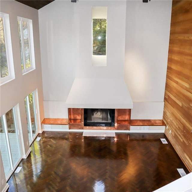 unfurnished living room featuring wood walls, a fireplace, and a towering ceiling