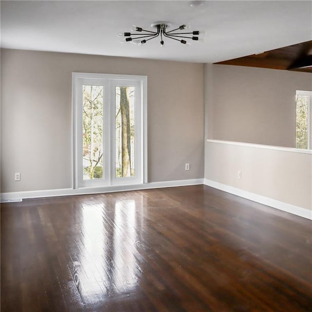 spare room with baseboards and wood finished floors