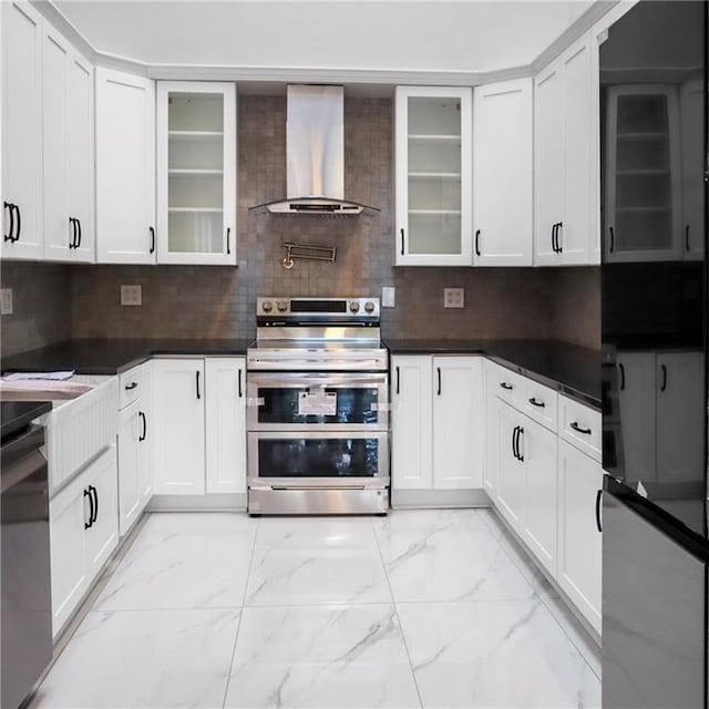 kitchen featuring wall chimney range hood, double oven range, marble finish floor, and backsplash