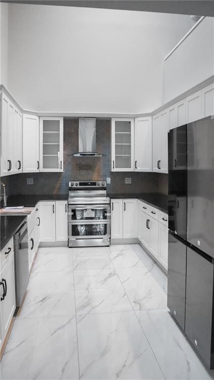 kitchen featuring marble finish floor, stainless steel appliances, wall chimney exhaust hood, and decorative backsplash