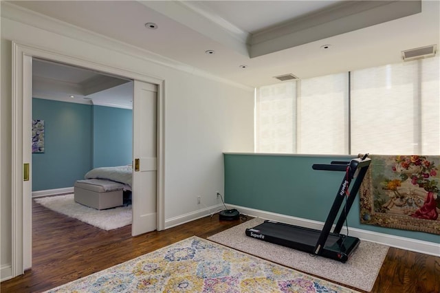 exercise area featuring dark hardwood / wood-style floors, ornamental molding, and a raised ceiling