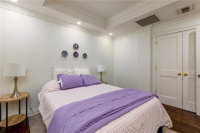 bedroom featuring visible vents, a tray ceiling, ornamental molding, recessed lighting, and wood finished floors