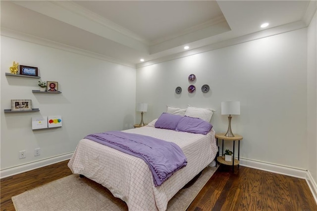 bedroom featuring crown molding, wood finished floors, baseboards, and a tray ceiling