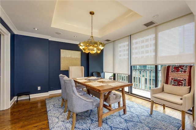 dining room with an inviting chandelier, dark hardwood / wood-style flooring, ornamental molding, and a raised ceiling