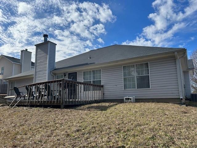 back of property featuring a wooden deck and a yard